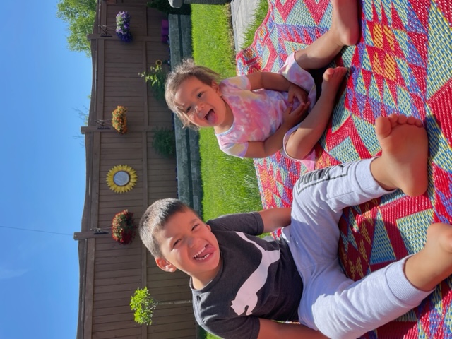 Les deux jeunes enfants de Samantha sont assis dehors sur une couverture.