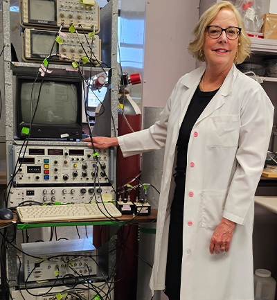 Mme Howlett se tient à côté de son équipement de recherche dans son laboratoire.