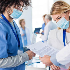  Un groupe de professionnels de la santé masqués regarde un papier.