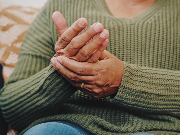 Une femme se masse les mains, laissant supposer de la douleur