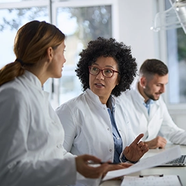 Un groupe de professionnels de la santé discutent à leur bureau.