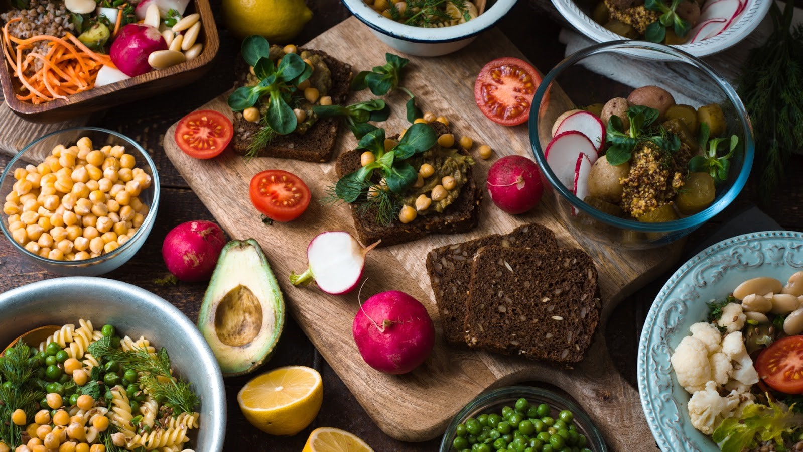Une table en bois couverte d’une variété d’aliments d’origine végétale, de salades et de collations.