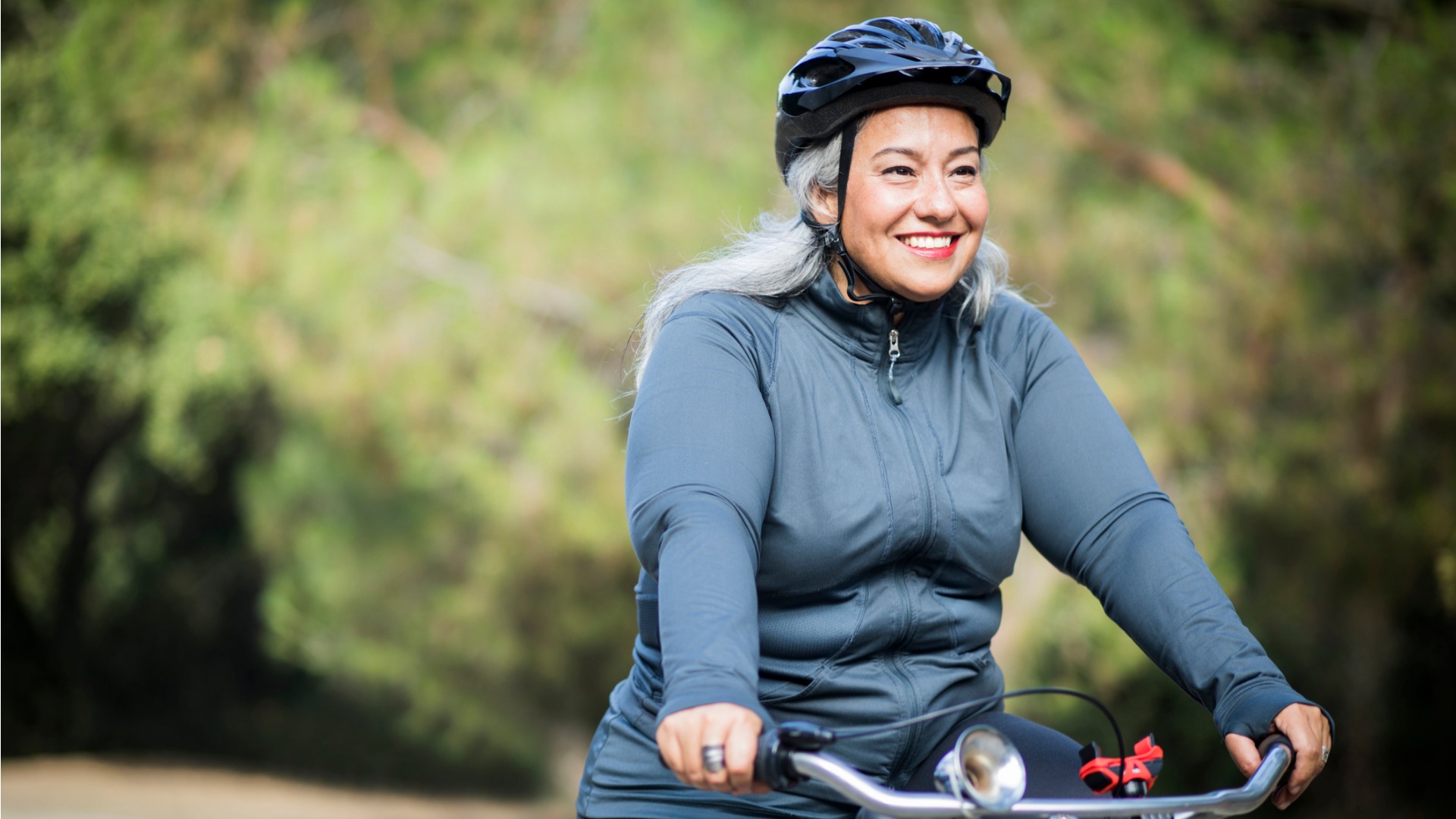 Une femme portant un casque protecteur et qui fait du vélo à l’extérieur.