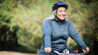 Une femme portant un casque protecteur et qui fait du vélo à l’extérieur.
